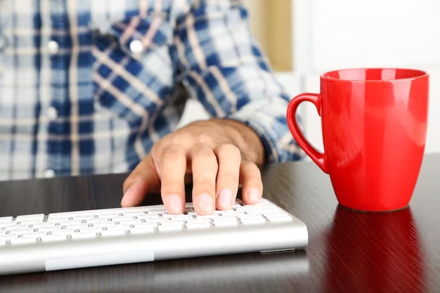 Male hand on keyboard next to red cup